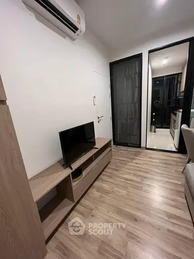 Modern living room with sleek wooden flooring and compact TV setup