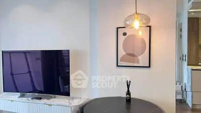 Modern living room with stylish decor and flat-screen TV, featuring elegant lighting and contemporary artwork.