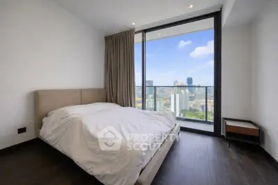 Modern bedroom with stunning city view from floor-to-ceiling windows in high-rise apartment.