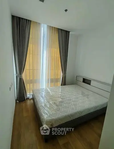 Modern bedroom with large window and elegant curtains, featuring a comfortable bed and wooden flooring.
