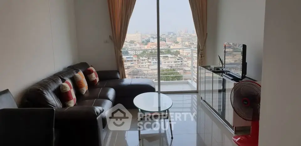 Modern living room with city view, leather sofa, and sleek TV setup in high-rise apartment.