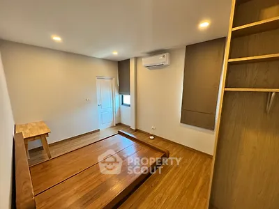 Spacious bedroom with wooden flooring and built-in wardrobe, featuring modern lighting and air conditioning.