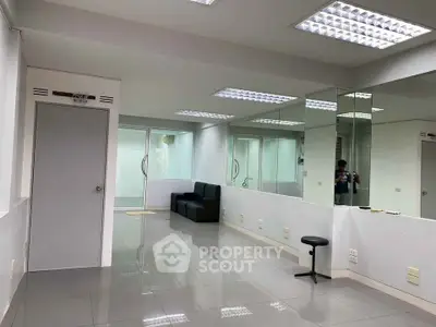 Spacious modern office space with mirrors and sleek tile flooring.