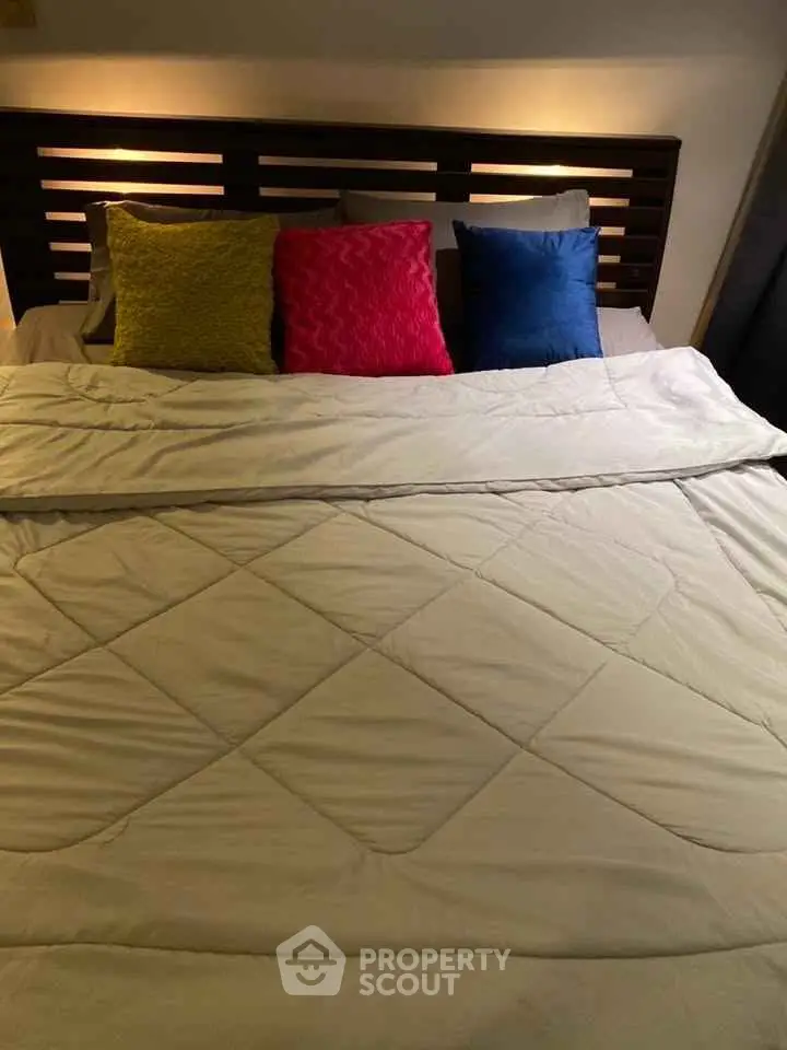Cozy bedroom with colorful pillows and modern headboard design.