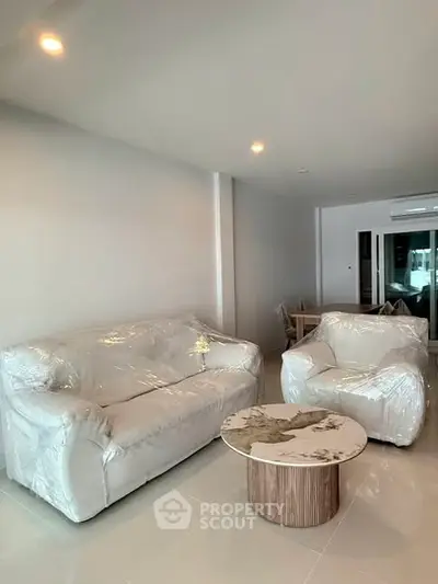 Modern living room with plastic-covered furniture and stylish coffee table in a contemporary apartment.
