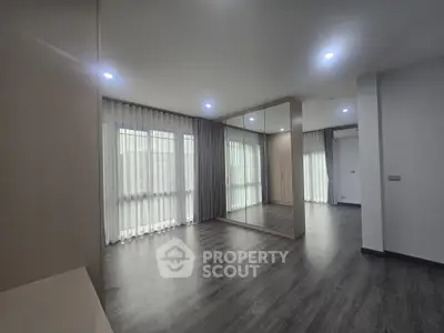 Spacious modern living room with large windows and mirrored wall