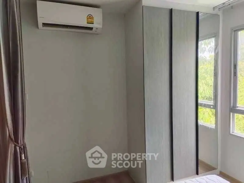 Modern bedroom with air conditioning and large windows offering natural light.