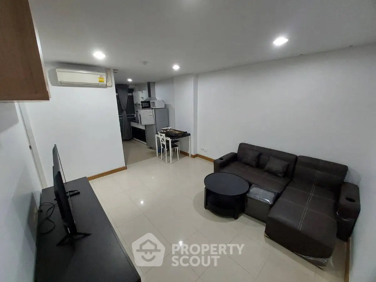 Modern living room with sleek furniture and open kitchen layout in a stylish apartment.