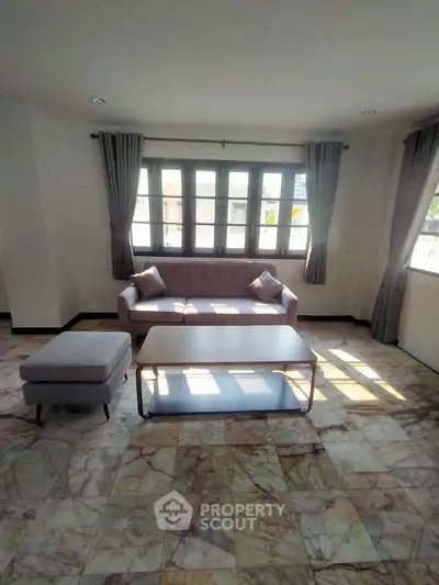 Spacious living room with elegant sofa and natural light through large windows.