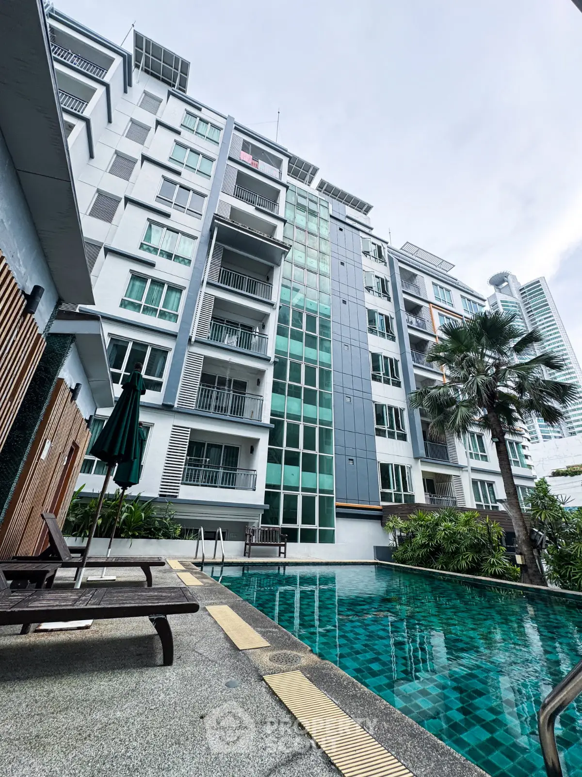 Modern condominium with pool and lush greenery in urban setting