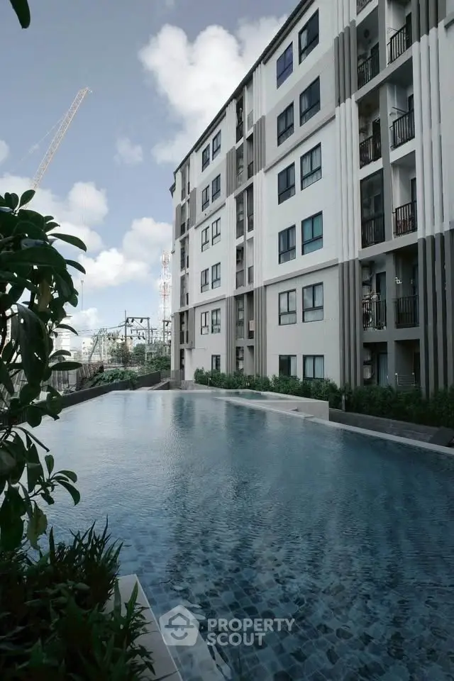 Modern apartment building with a luxurious outdoor pool and lush greenery.