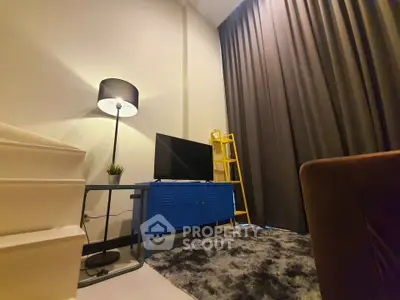 Modern living room with stylish decor, featuring a blue TV stand, cozy rug, and elegant floor lamp.