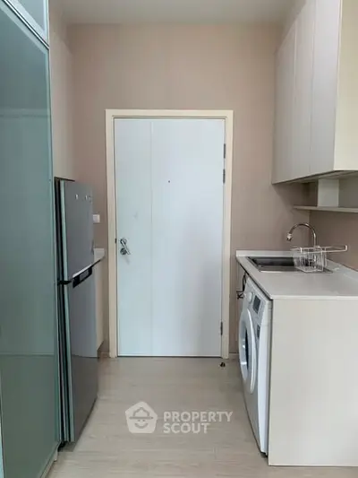 Modern kitchen with washing machine and fridge in compact layout.