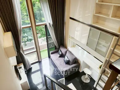 Stunning loft-style living room with high ceilings and large windows overlooking greenery.