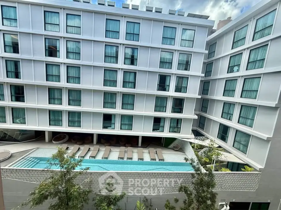 Modern apartment building with pool and sun loungers, offering a luxurious urban lifestyle.