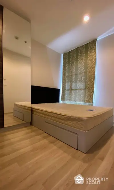 Spacious bedroom with modern wooden flooring and elegant patterned wallpaper, featuring a large bed with storage drawers.