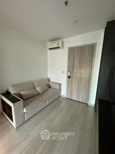 Modern living room with sleek sofa and air conditioning in a minimalist apartment.