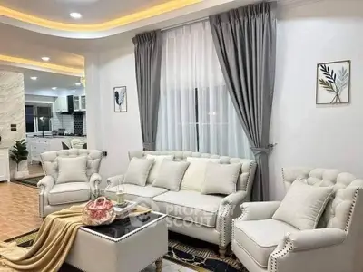 Elegant living room with plush seating and modern decor, open layout to stylish kitchen.