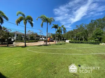 Spacious green garden area with palm trees in a residential community, perfect for outdoor activities.