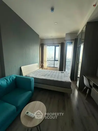 Modern bedroom with city view, featuring a cozy bed, stylish sofa, and sleek wooden flooring.