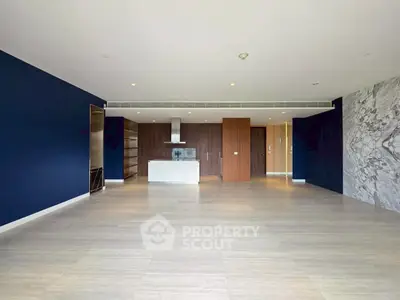 Spacious modern living room with open kitchen and elegant marble accent wall.