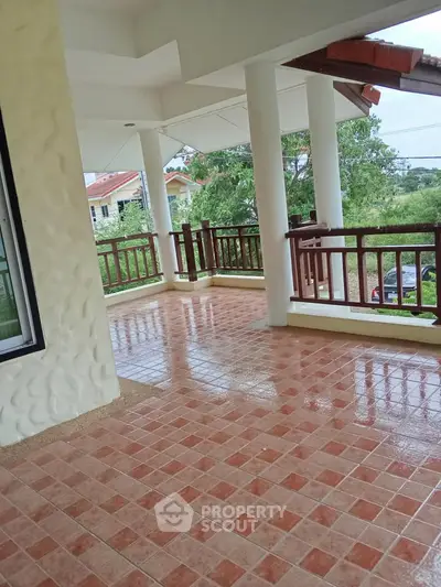 Spacious tiled balcony with wooden railings and scenic view.