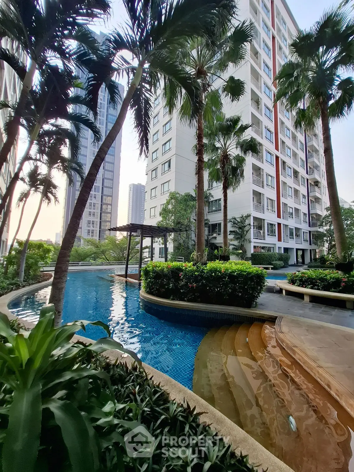 Luxurious residential building with lush garden and inviting pool area.