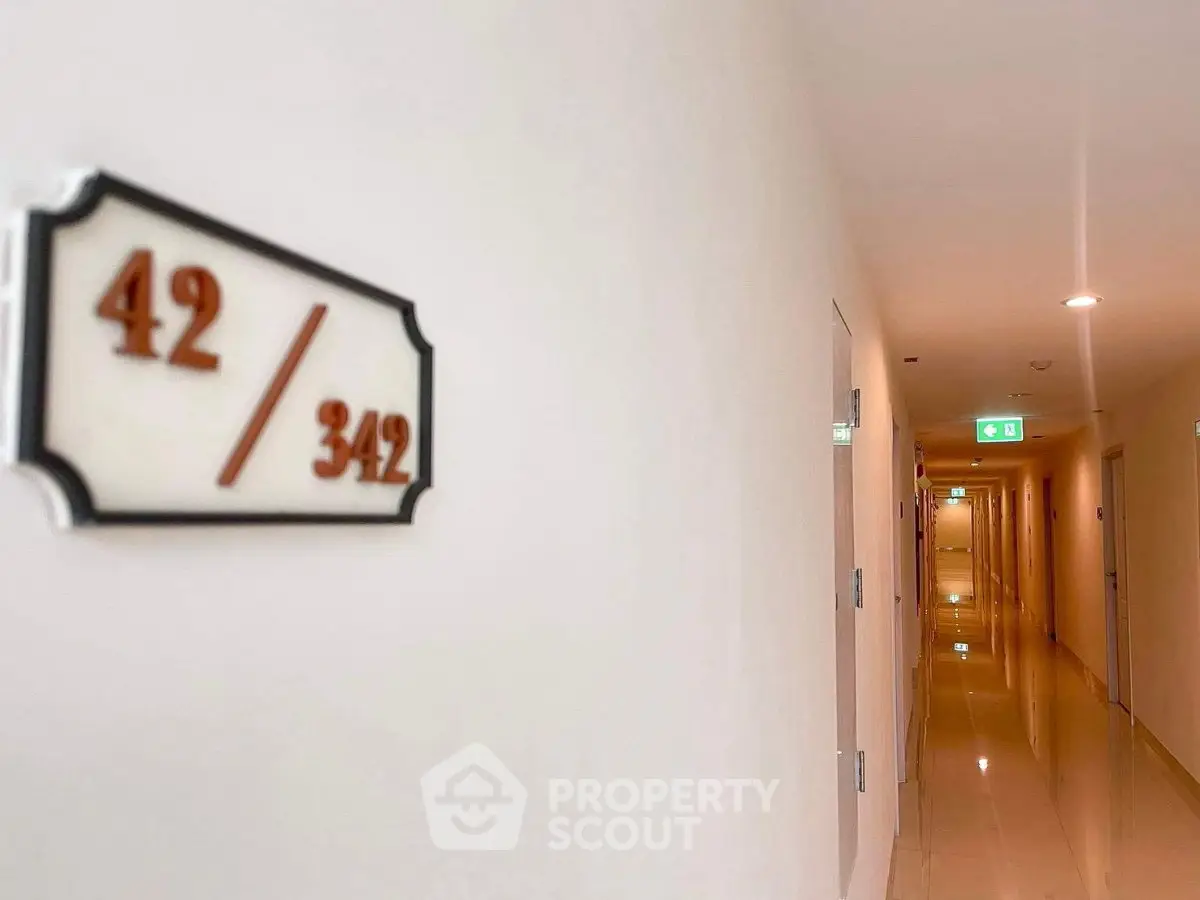 Modern apartment corridor with room number signage and polished floors.