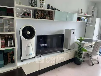 Modern living room with sleek storage, TV, and stylish decor in a contemporary apartment.