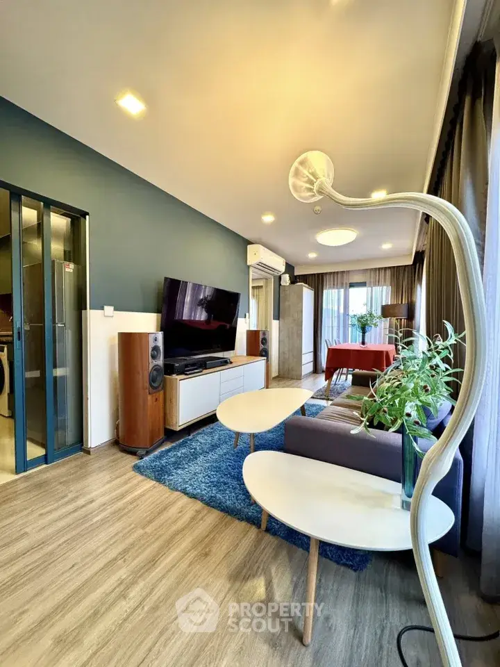 Modern living room with stylish decor, large TV, and elegant lighting in a cozy apartment.