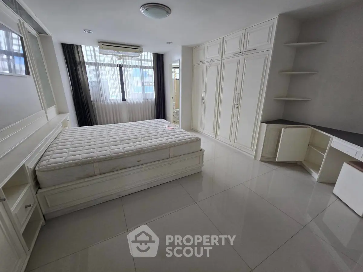Spacious bedroom with built-in storage and large windows in modern apartment