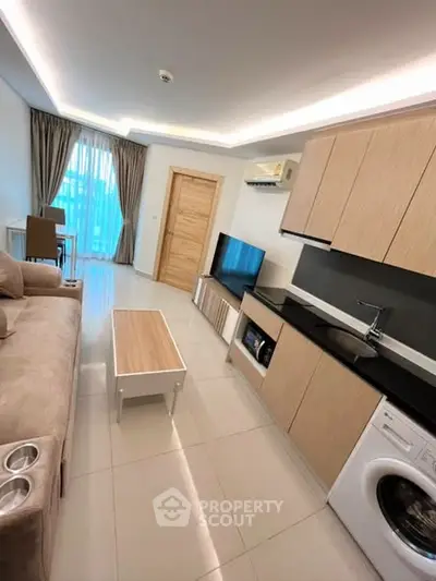 Modern living room with sleek kitchen, cozy sofa, and natural light from large window.