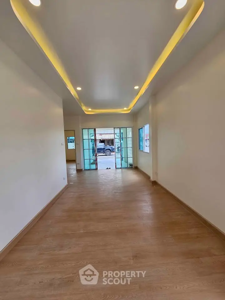Spacious interior with modern lighting and wooden flooring, ideal for versatile living space.