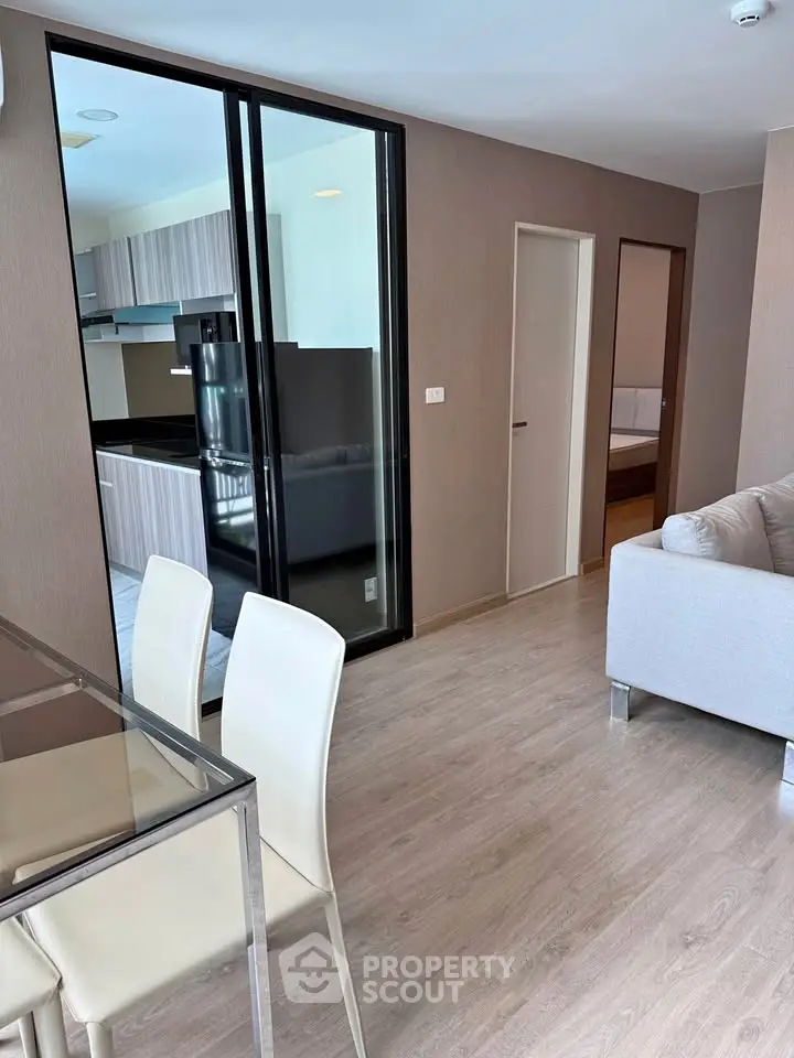 Modern open-plan living room with sleek kitchen and dining area in stylish apartment.