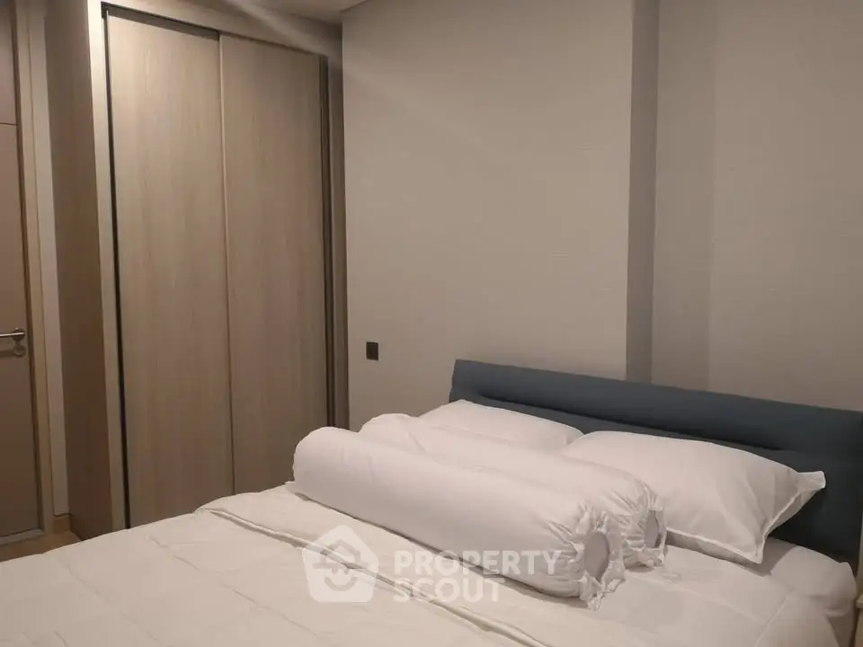 Modern bedroom with sleek wardrobe and cozy bedding in a contemporary apartment.