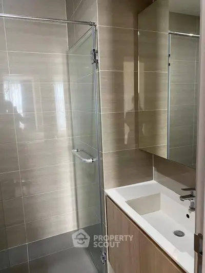 Modern bathroom with sleek glass shower and stylish vanity in contemporary apartment.