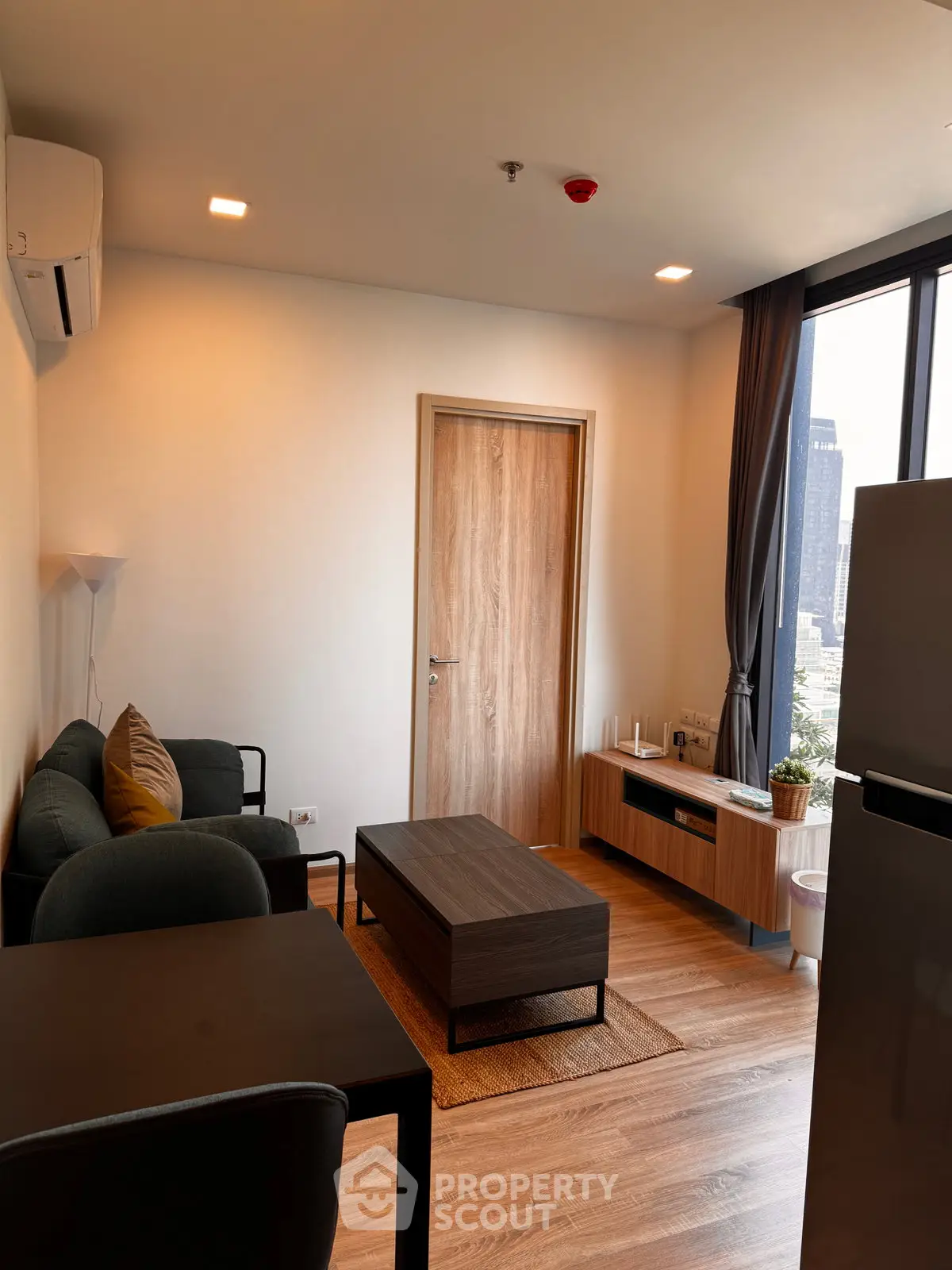 Modern living room with city view, featuring sleek furniture and wooden flooring.