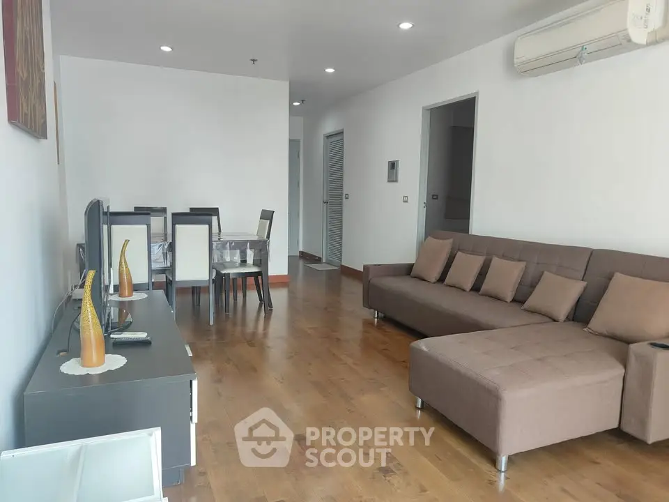 Spacious living room with modern furniture and wooden flooring, perfect for family gatherings.