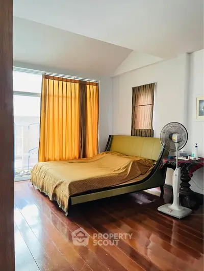 Spacious bedroom with elegant wooden flooring and large windows for natural light