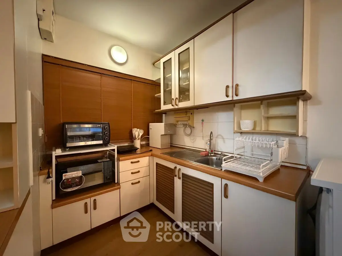 Charming kitchen with wooden cabinets and modern appliances in cozy apartment.