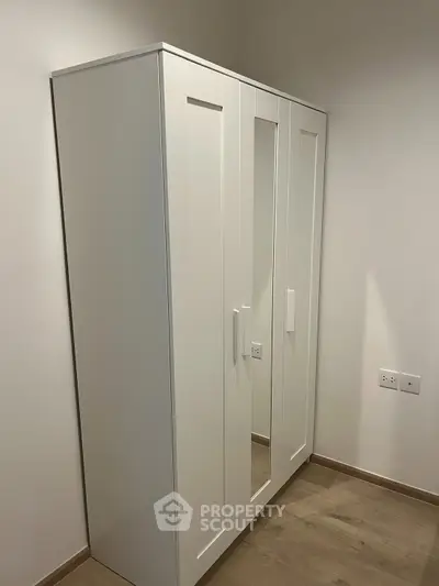 Modern white wardrobe in a minimalist bedroom with wooden flooring.