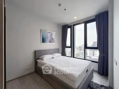 Modern bedroom with large windows offering stunning city views in a high-rise apartment.