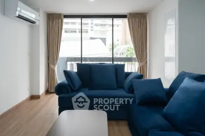 Modern living room with blue sofas and large window offering natural light and city view.