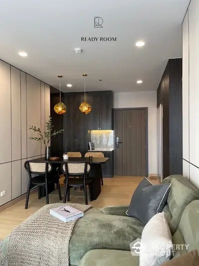 Modern apartment interior with chic decor, featuring a plush green sofa, elegant golden pendant lights, and a cozy dining area, perfect for urban living.