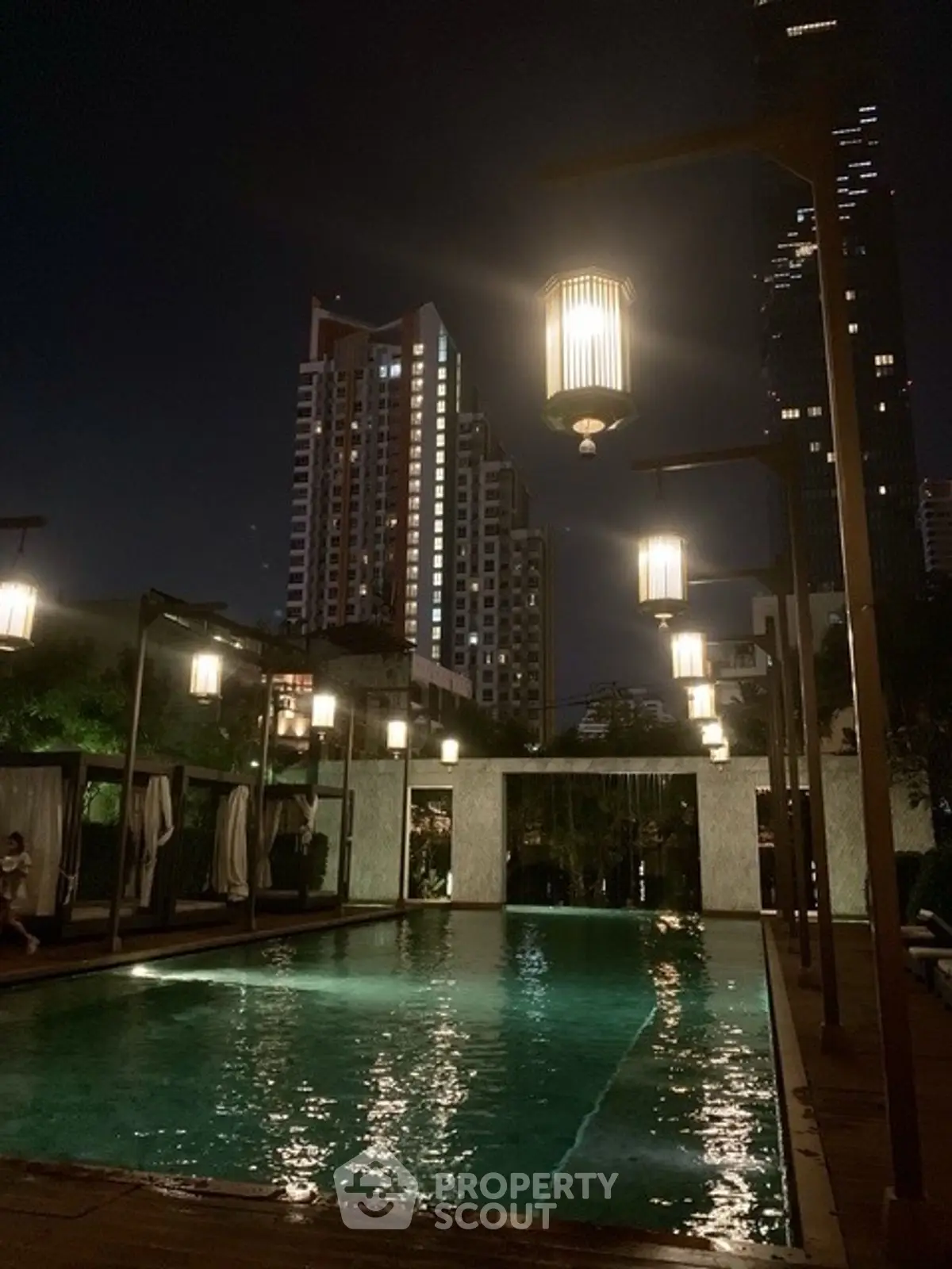 Luxurious rooftop pool with ambient lighting and city skyline view at night.