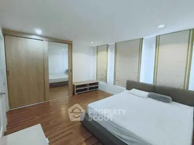 Spacious bedroom with wooden flooring and large mirrored wardrobe