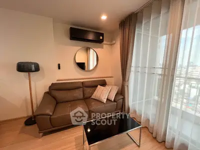 Modern living room with leather sofa, stylish lamp, and city view through large windows.