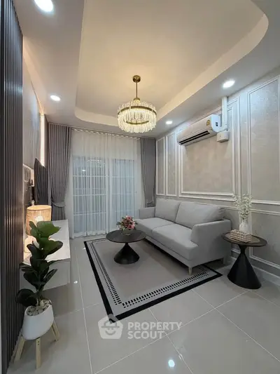 Elegant living room with modern decor, featuring a stylish chandelier, sleek sofa, and tasteful accents.