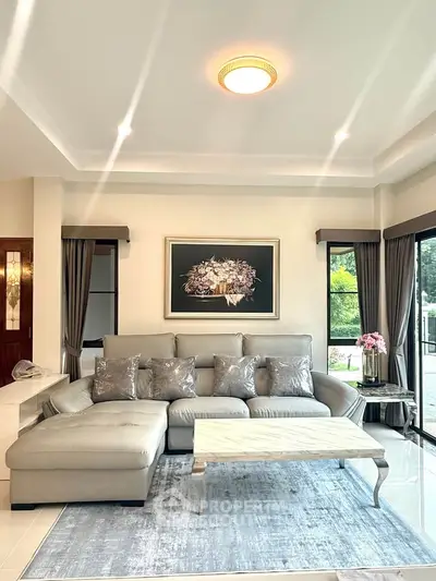 Elegant living room with modern sofa and stylish decor, featuring large windows and natural light.