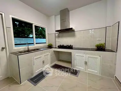 Modern kitchen with sleek countertops and gas stove, featuring elegant cabinetry and large window view.
